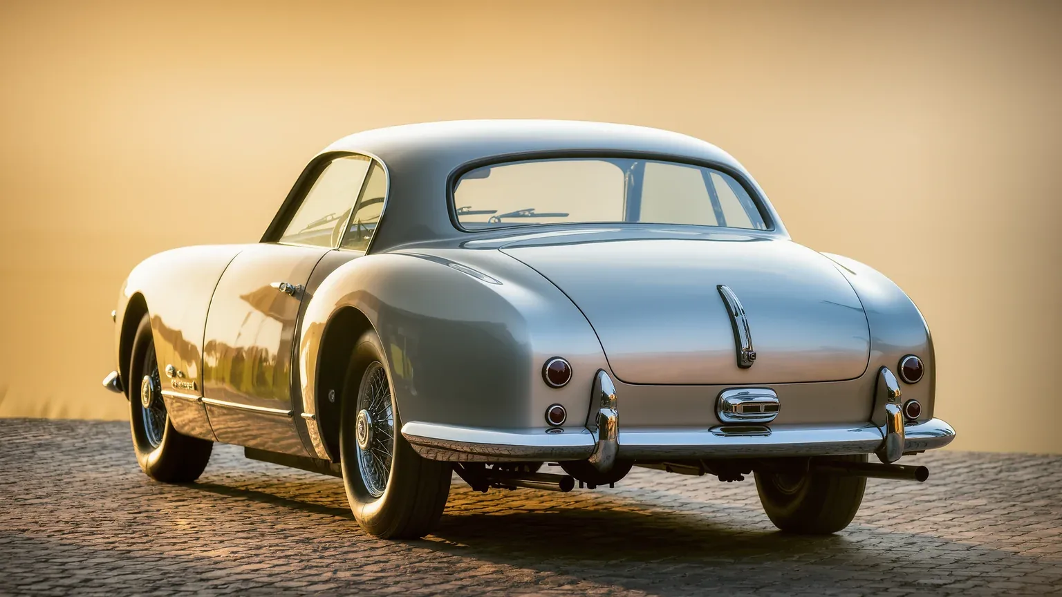 A classic coupe photographed against low sun on a cobbled surface