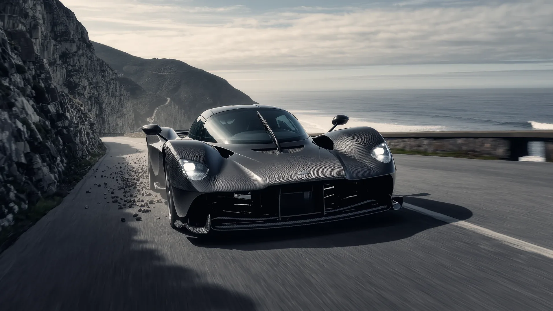 A supercar on a coastal road with the sea and cliffs behind it